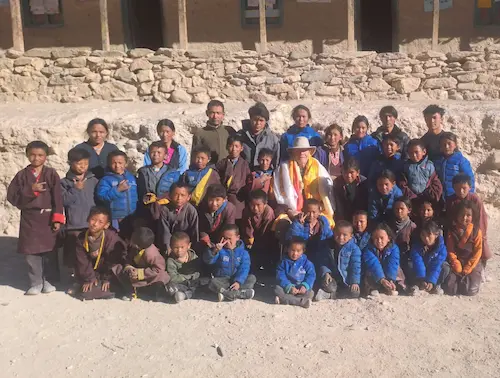 group photo of childrens with snowman after it had melted smiling.
